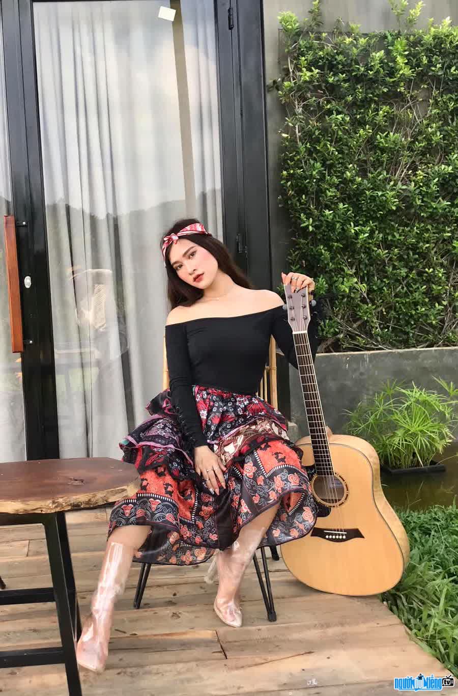 Hình ảnh ca sĩ Minh Chi tạo dáng bên chiếc đàn ghi ta