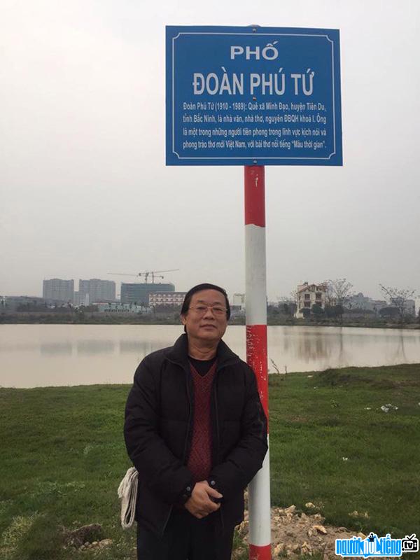 Hình ảnh nghệ sĩ ưu tú Phú Thăng đứng dưới tấm biển tên phố có tên cha