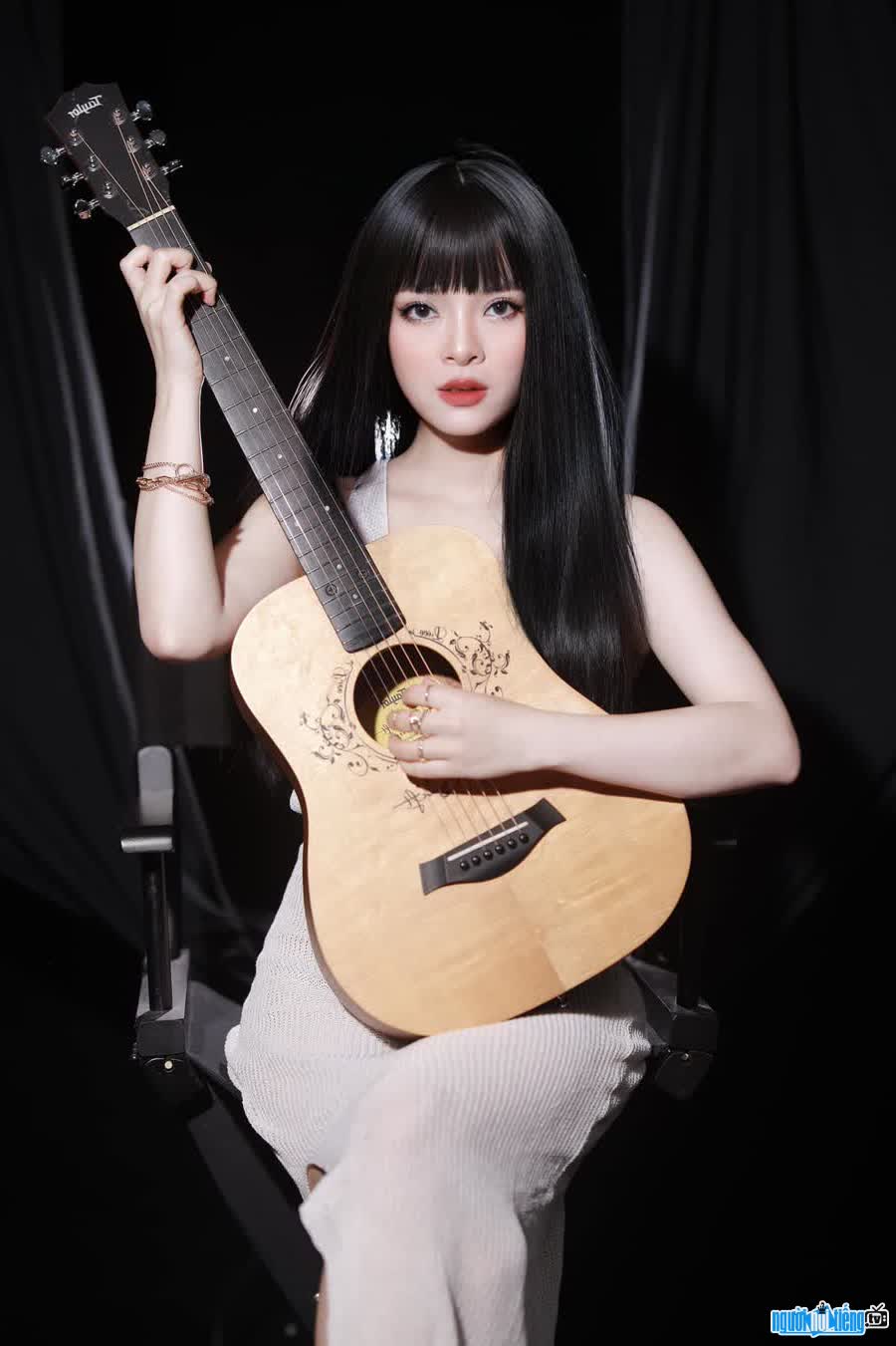 Hình ảnh ca sĩ Nguyễn An An đang ôm chiếc đàn ghita quen thuộc