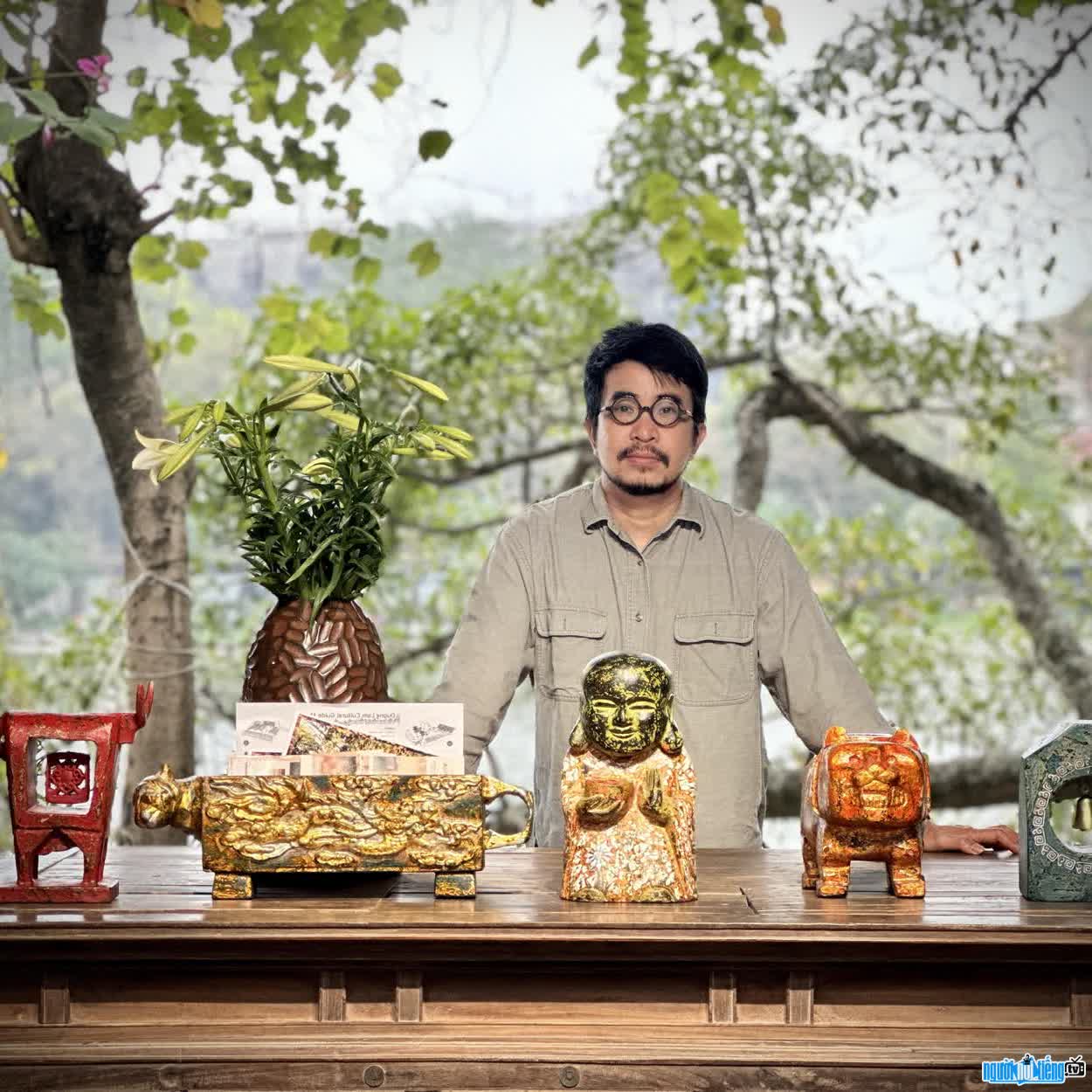 Image of artist Nguyen Tan Phat next to his works