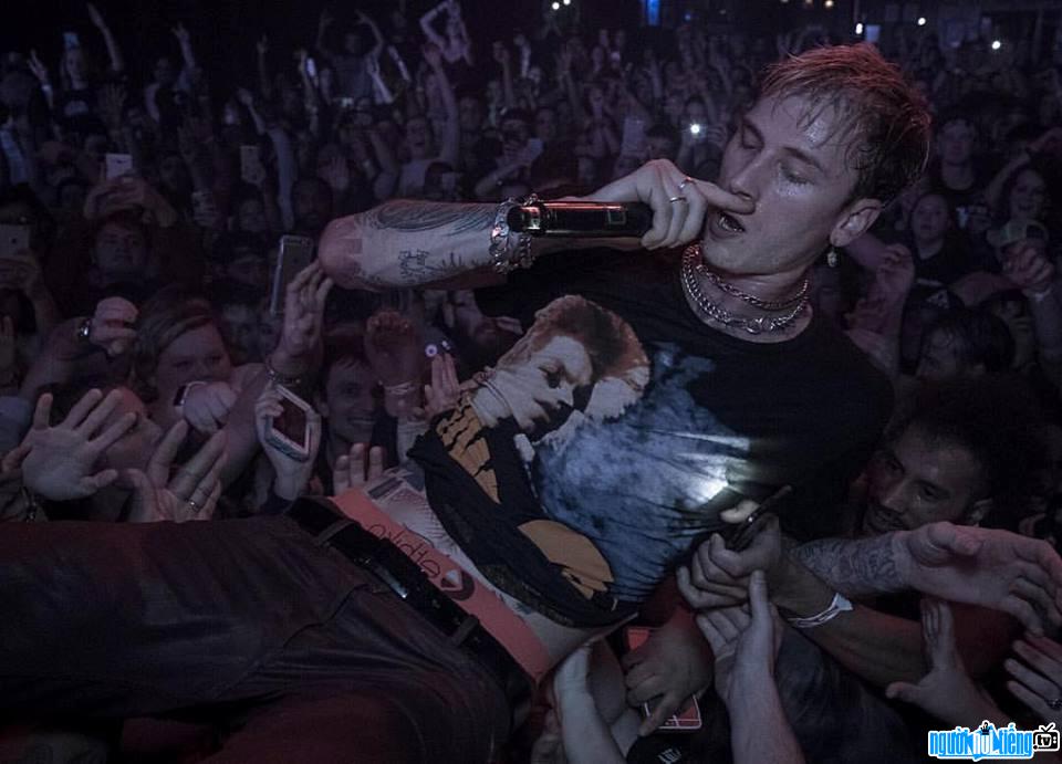 Image of rapper Machine Gun Kelly performing in the audience's arms 