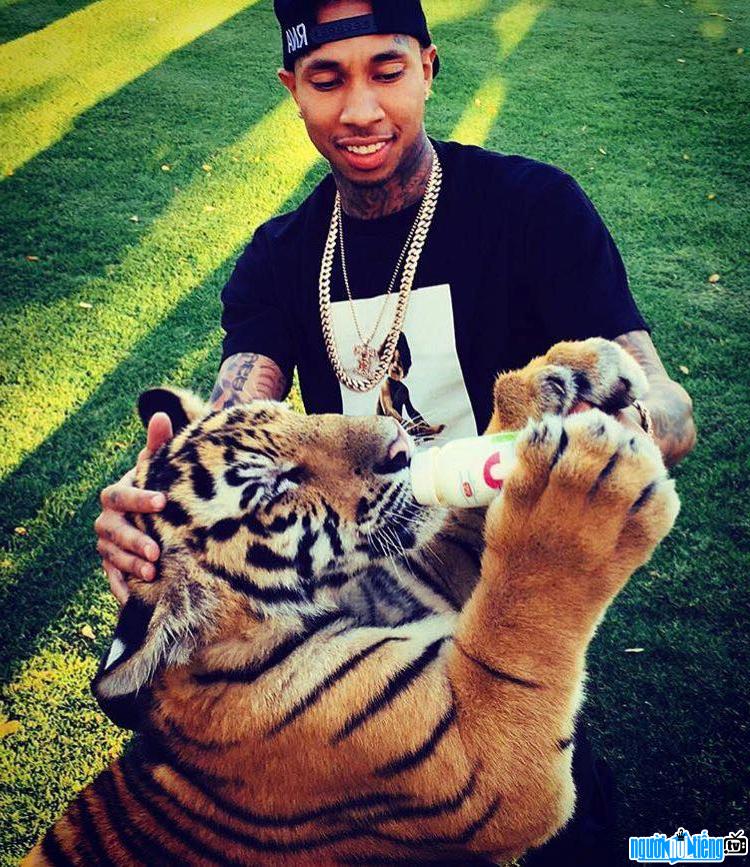 Picture of male rapper Tyga feeding a tiger with milk