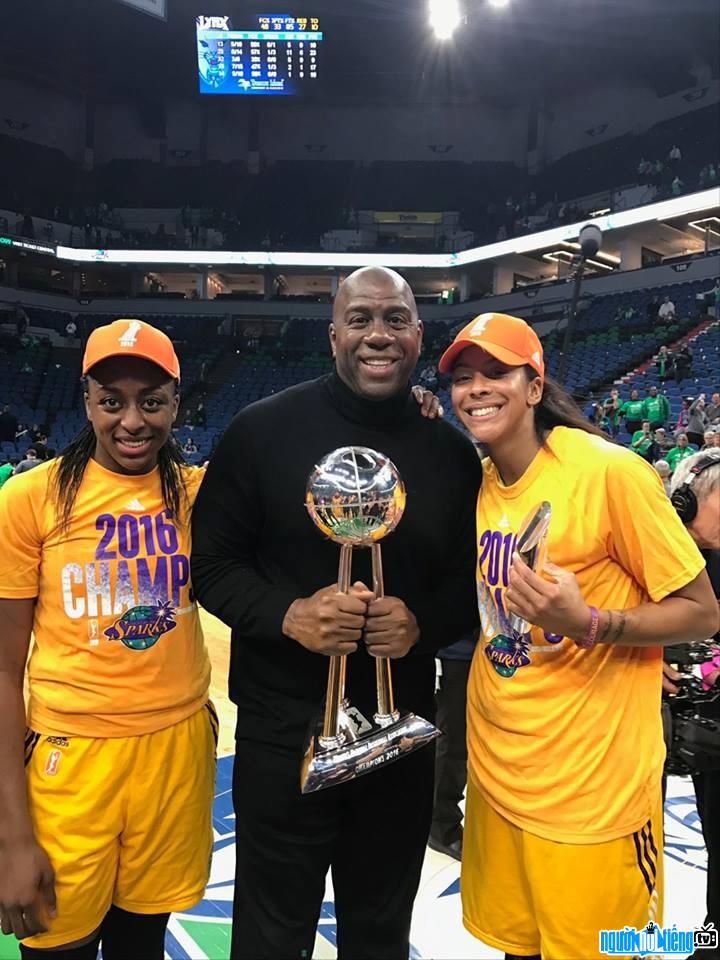 A photo of former Magic Johnson basketball player holding a championship trophy with young athletes