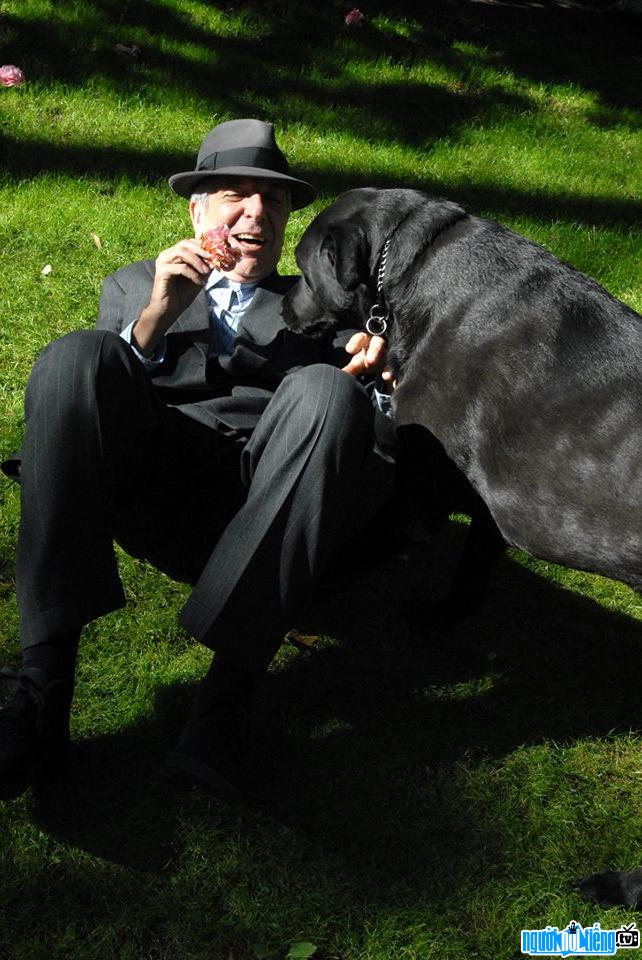 The image of singer Leonard Cohen is playing with his pet dog