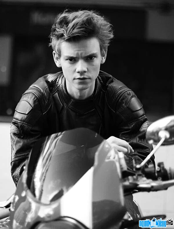 Image of actor Thomas Sangster showing off his masculinity with a motorcycle