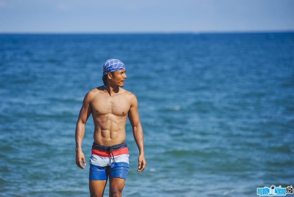 Image of actor David Pham showing off his standard body on the beach