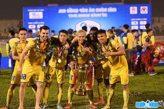 Player Pham Xuan Manh and his teammates lift the championship cup