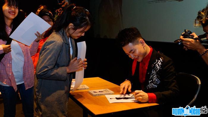 Hình ảnh ca sĩ Tùng Mini đang ký tặng fan